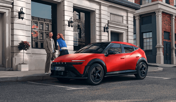 Rode elektrische Hyundai IONIQ 3 geparkeerd in een stad met twee mensen op de achtergrond